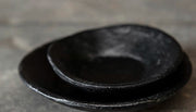 Oude zwarte metalen kaarsschotel met doorleefde matte look