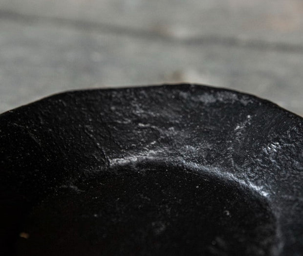 Oude zwarte metalen kaarsschotel met doorleefde matte look